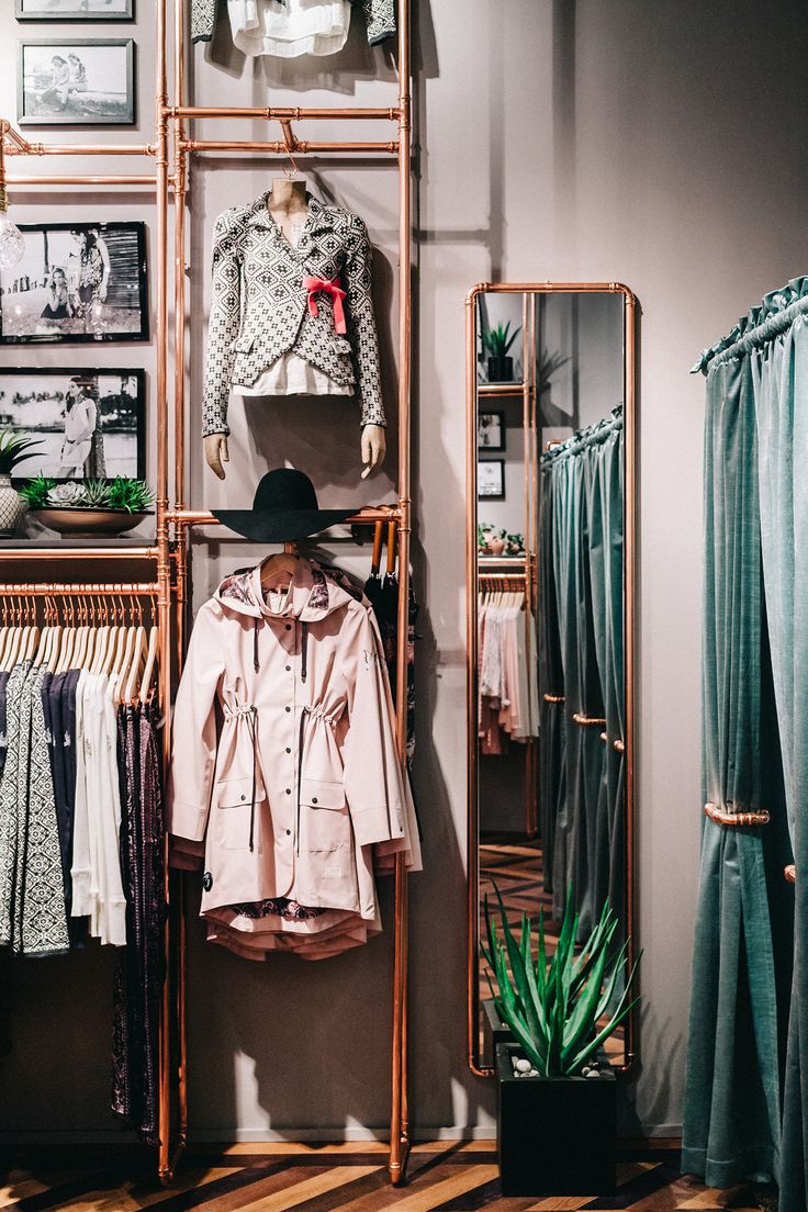 a clothing rack with clothes and hats hanging on it's sides in a store