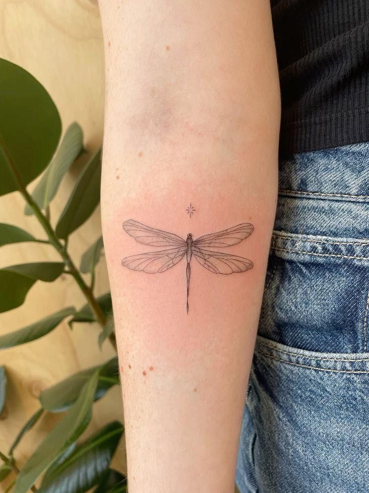 a small dragonfly tattoo on the arm