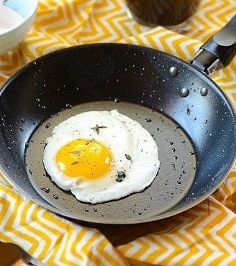 an egg frying in a skillet on top of a yellow and white towel