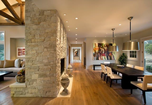 a living room filled with furniture and a fire place next to a dining table on top of a hard wood floor