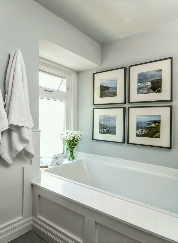 a white bath tub sitting next to a window with pictures on the wall above it