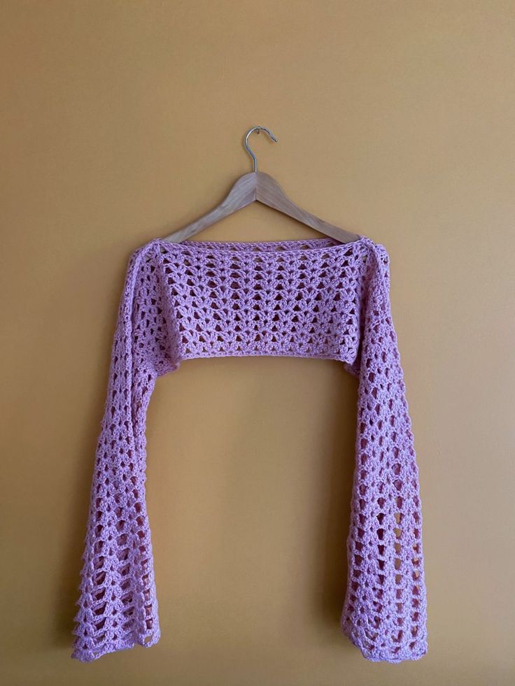 a crocheted sweater hanging on a hanger