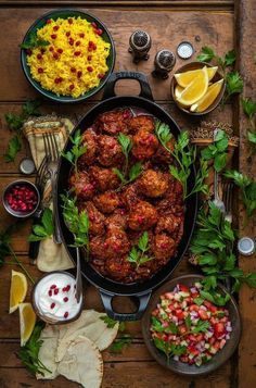 an overhead view of meatballs in a pan surrounded by other foods and garnishes