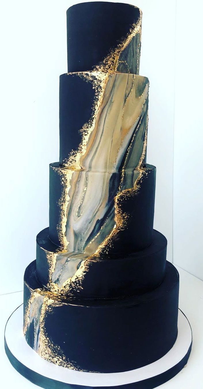 a three tiered black and gold wedding cake with marbled decoration on the side