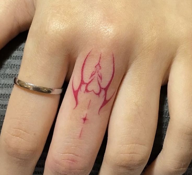 a woman's hand with a red ink tattoo on the middle finger and an arrow in the middle