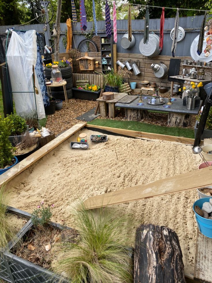 an outdoor area with sand, plants and pots