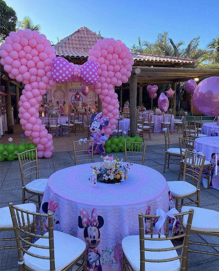 a minnie mouse themed birthday party with pink balloons and mickey mouse decorations on the tables