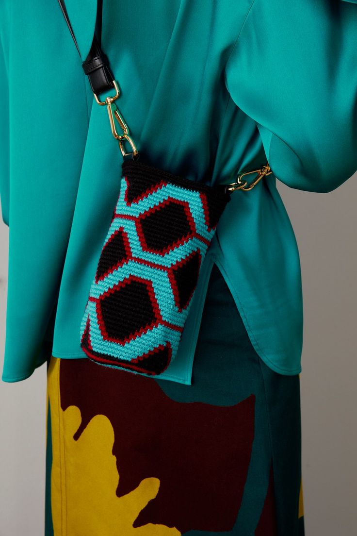 a close up of a person wearing a blue shirt and holding a small handbag