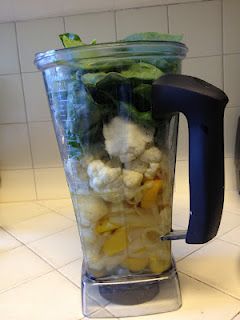 a blender filled with lots of vegetables on top of a white tiled kitchen counter