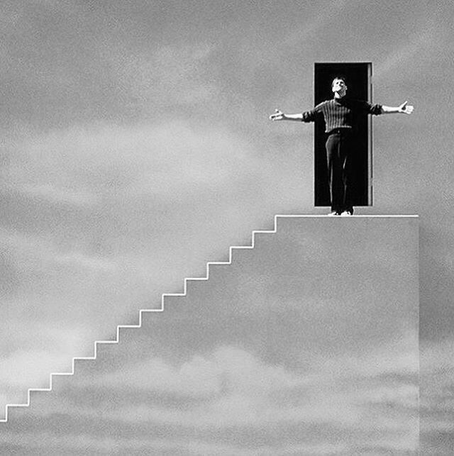 a man standing on top of a stair case with his arms outstretched in the air