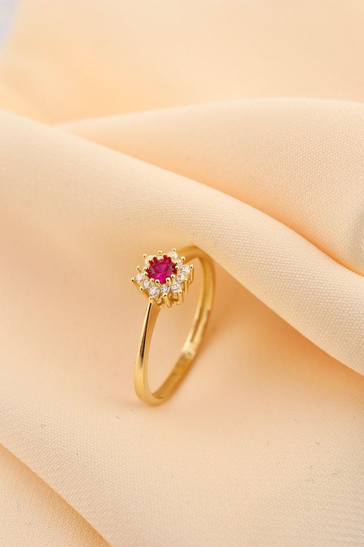 a close up view of a gold ring with a red stone