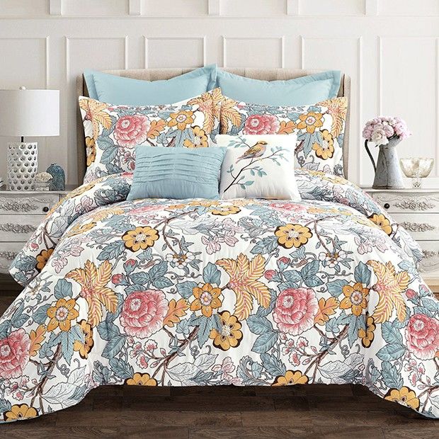 a bed with blue and pink flowers on it in a room next to a dresser