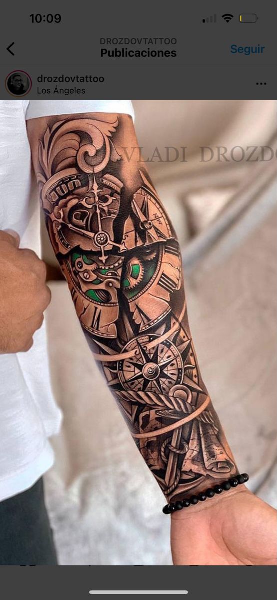 a man with a tattoo on his arm and wrist is holding a clock in his hand