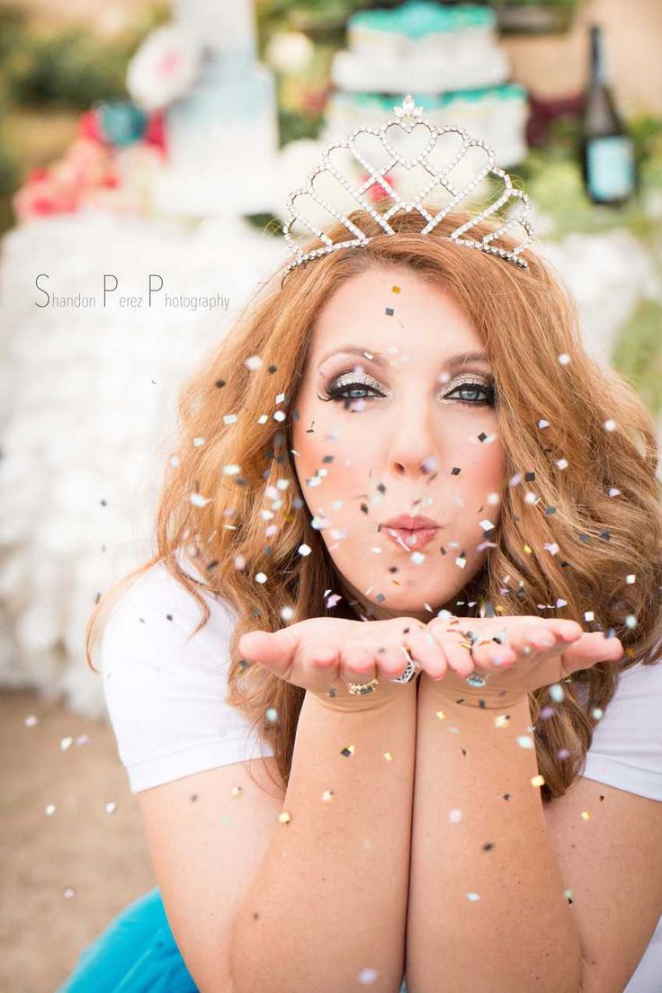 a woman wearing a tiara is sitting on the ground with confetti all over her face