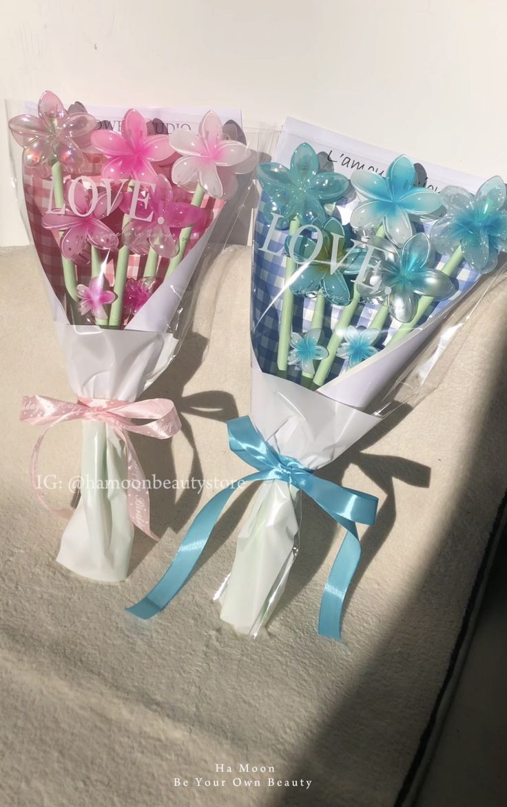 two bouquets of flowers are wrapped in cellophane and tied with blue ribbon