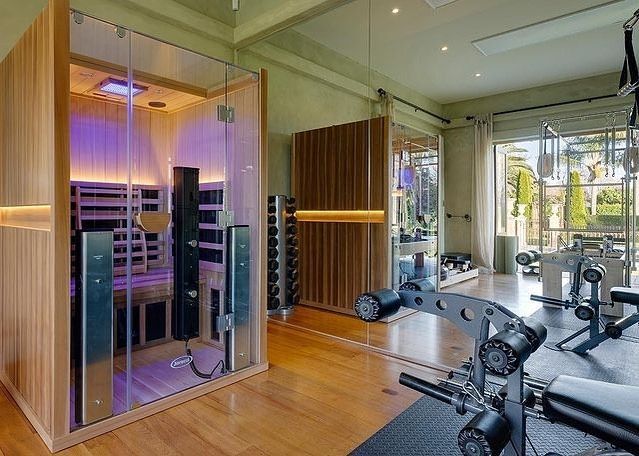 a home gym with an indoor saunat and exercise equipment in the foreground