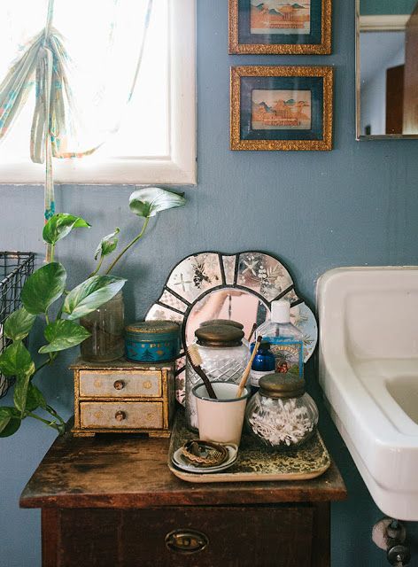 a bathroom with blue walls and pictures on the wall next to a wooden dresser topped with items