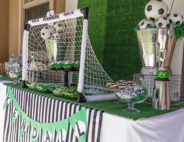 a table topped with soccer balls and cupcakes next to a goalie net