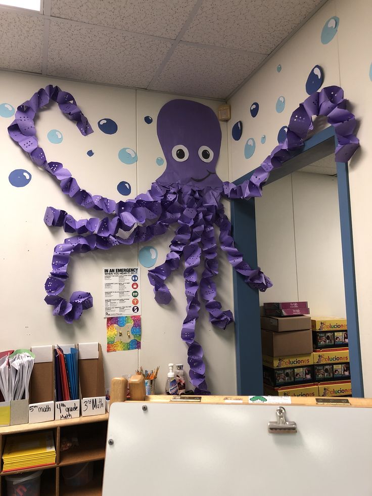 an octopus made out of purple tissue paper is hanging on the wall in front of a classroom