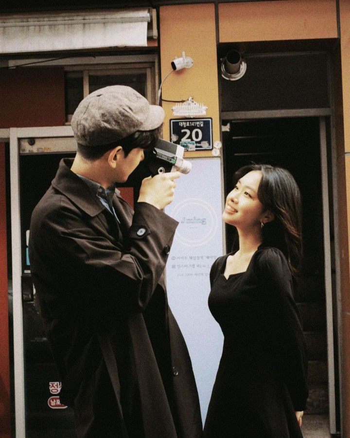 a man and woman standing next to each other in front of a sign with the number 20 on it