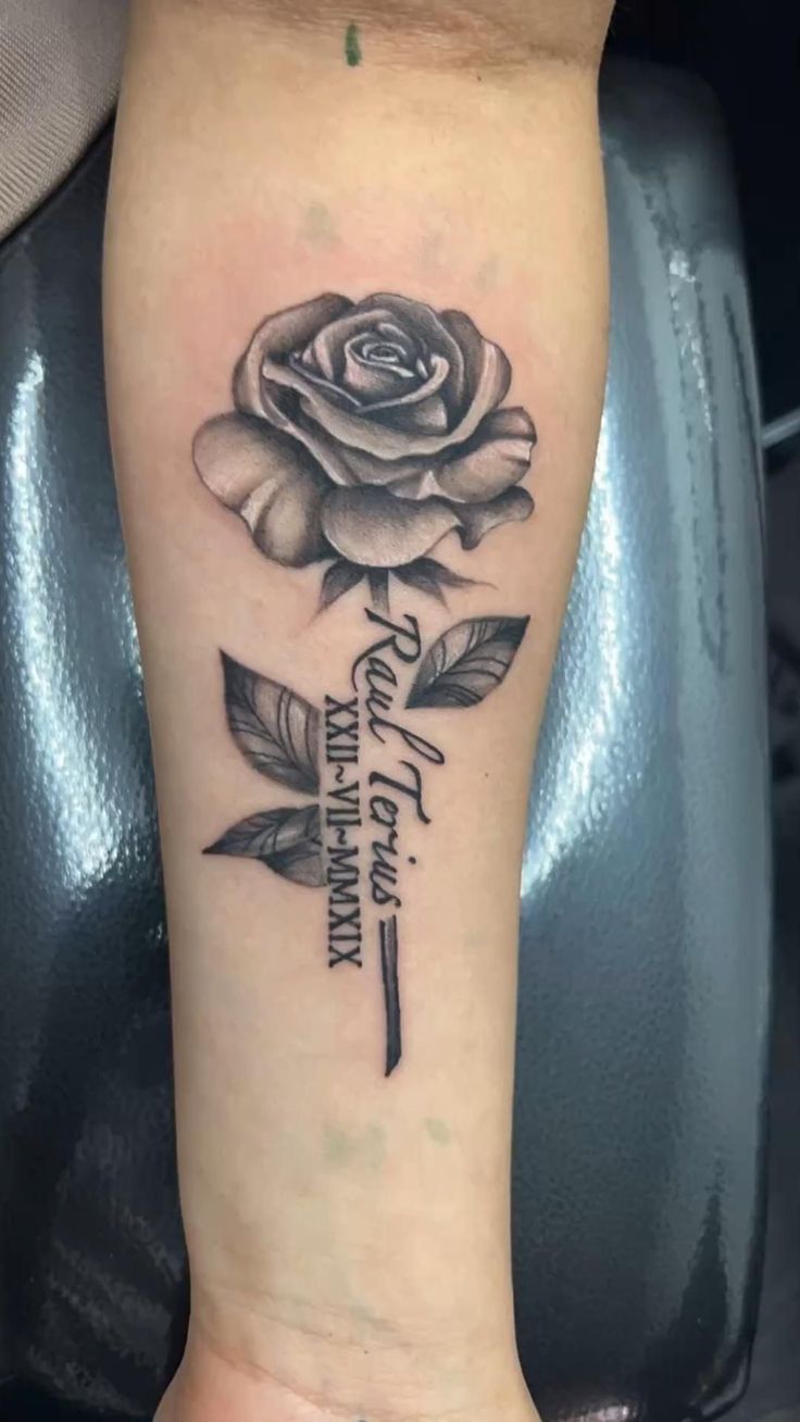 a black and white rose tattoo on the arm with words written below it, in cursive font