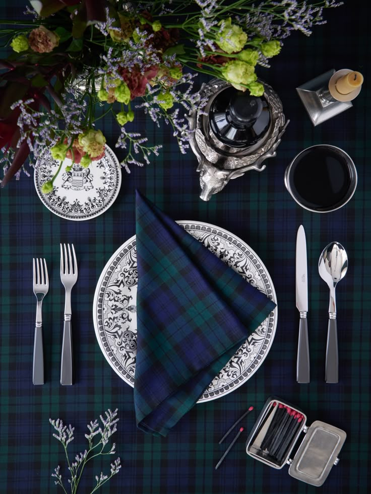 the table is set with silverware and plaid napkins