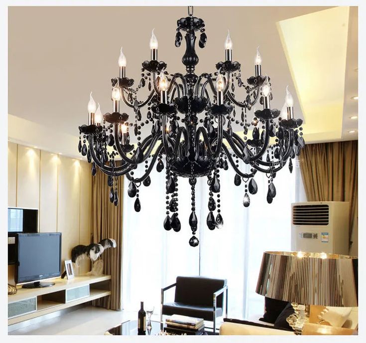 a black chandelier hanging from the ceiling in a living room next to a window