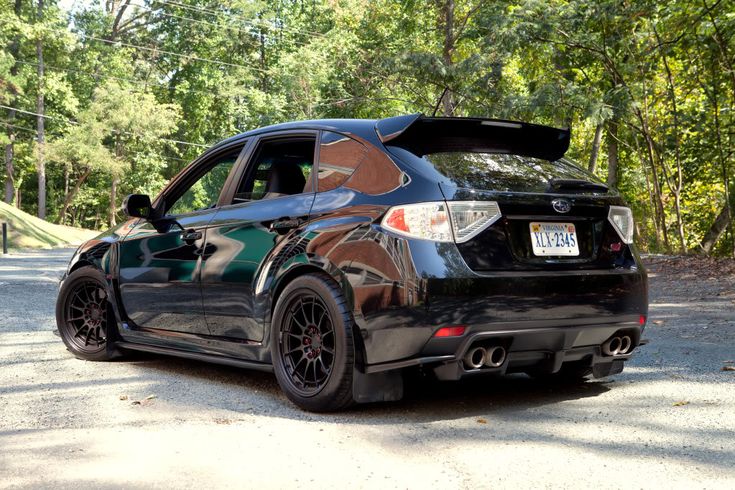 a black subarunt parked on the side of a road with trees in the background