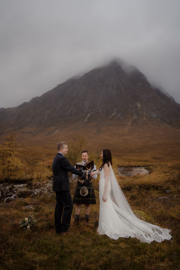 a bride and groom standing in front of a mountain