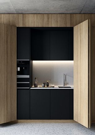 an open kitchen with black cabinets and white counter tops, along with a wooden wall