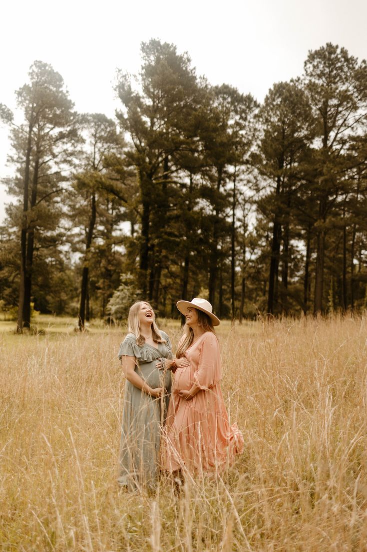 two women standing in tall grass with trees in the background