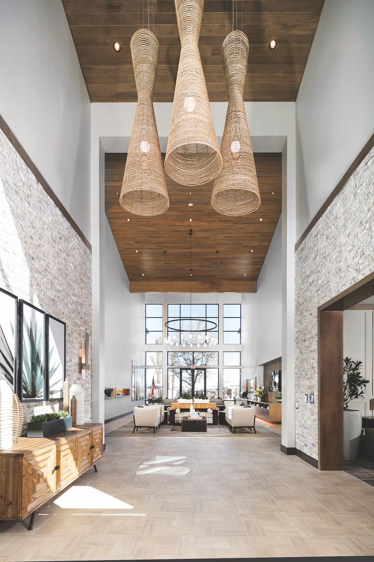 a large living room with high ceilings and wood accents on the ceiling is decorated in natural materials