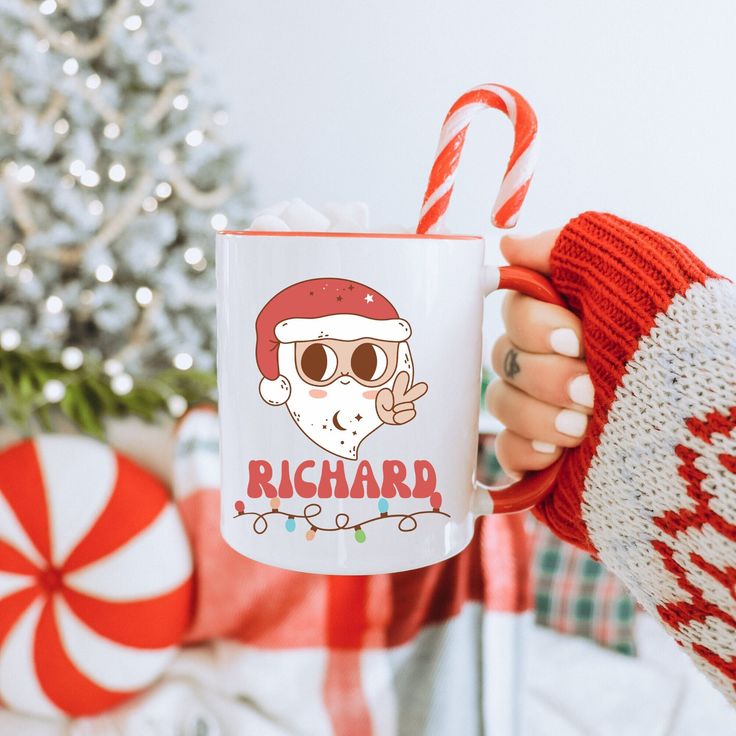 a person holding a coffee mug in front of a christmas tree with candy canes