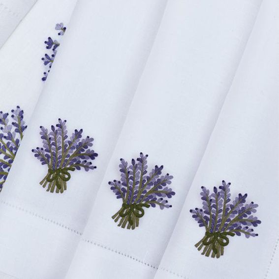 three napkins with embroidered lavender flowers on them