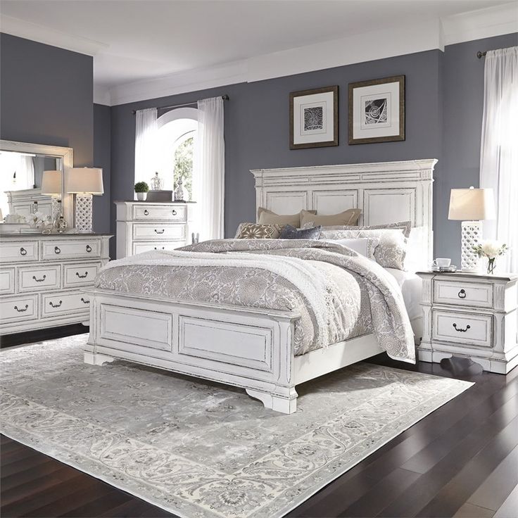 a white bed sitting on top of a hard wood floor next to a dresser and mirror