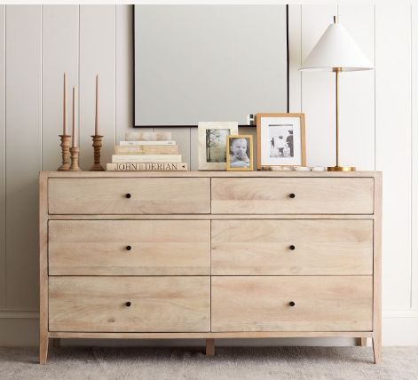 a wooden dresser with pictures and candles on top