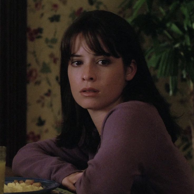 a woman sitting at a table with a plate of food in front of her, looking to the side