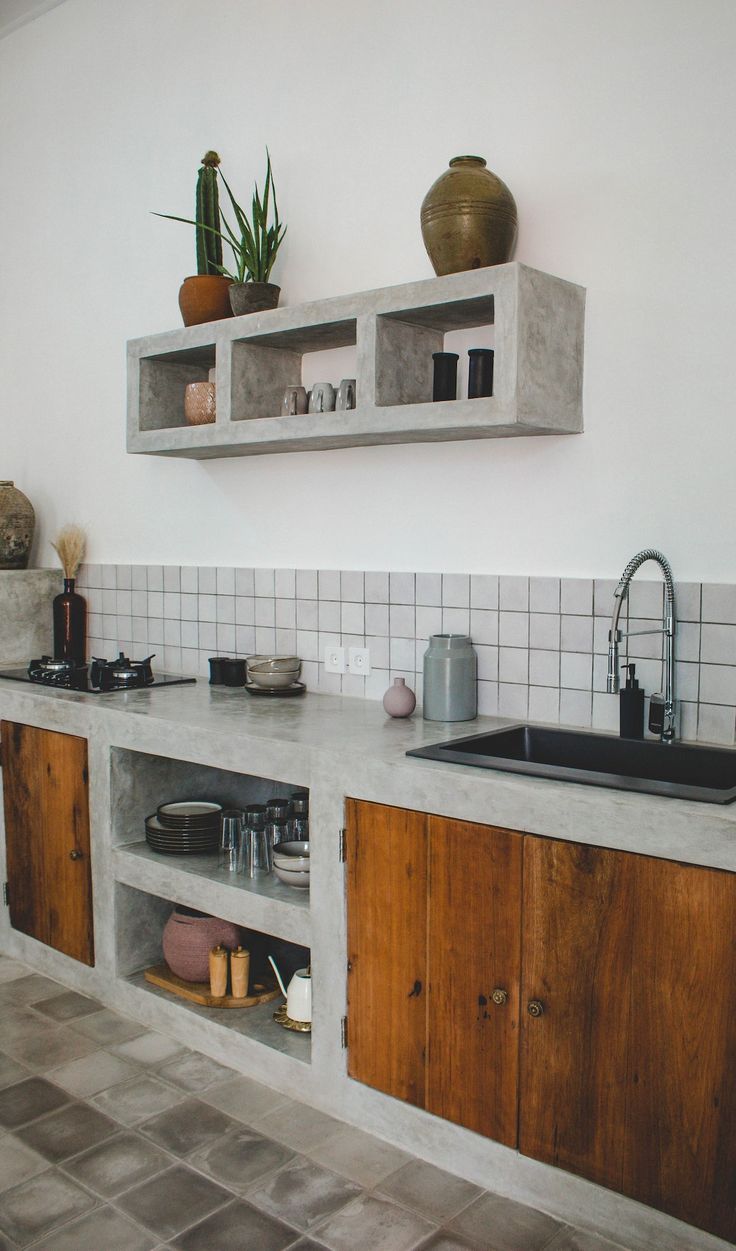 a kitchen with wooden cabinets and white tiled walls is pictured in this image, there are plants on the shelves above the sink