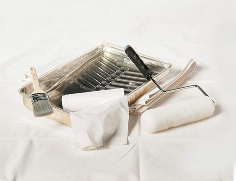 an assortment of kitchen utensils and cleaning supplies on a white sheeted surface