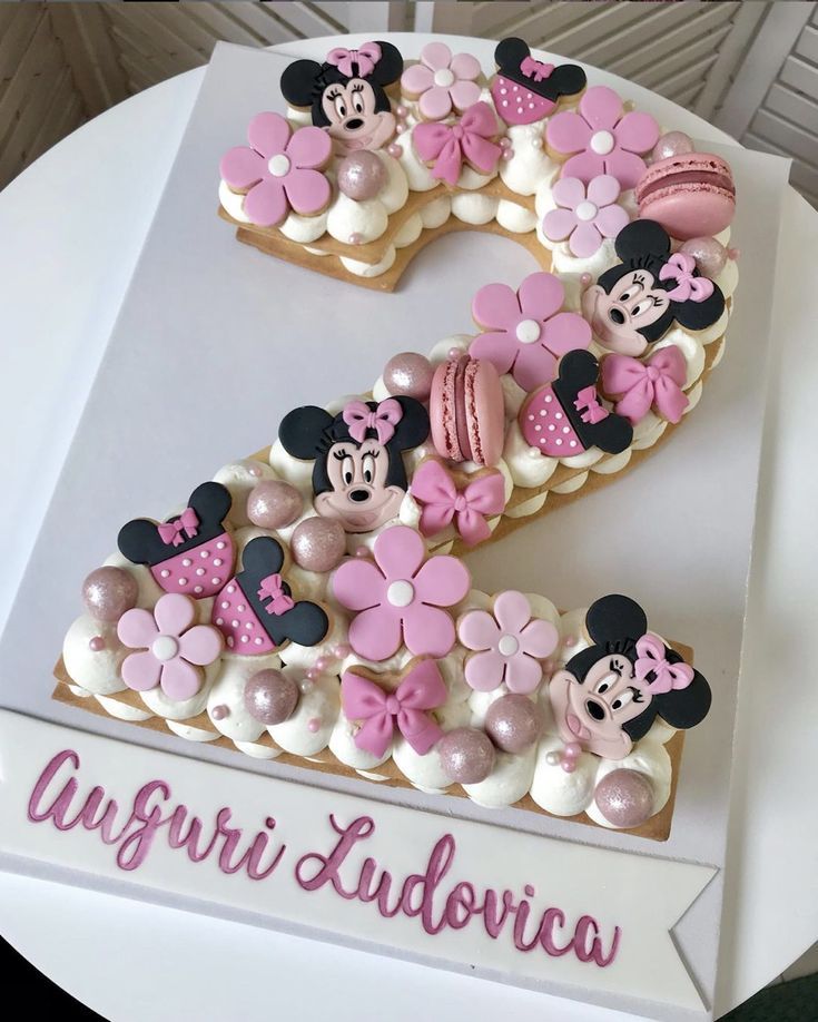 a cake shaped like the number one with minnie mouses on it's side