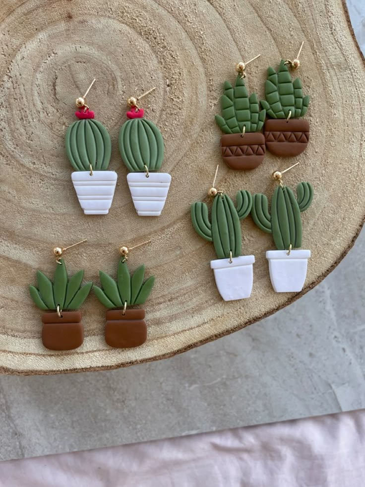 small cactus shaped earrings on a wooden platter with white and brown pots filled with cacti