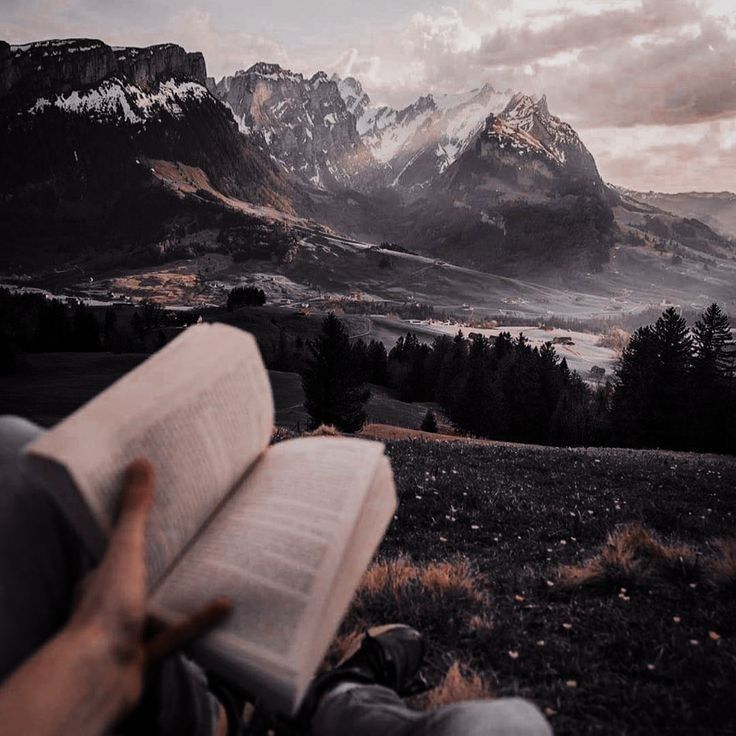 someone is reading a book in the mountains