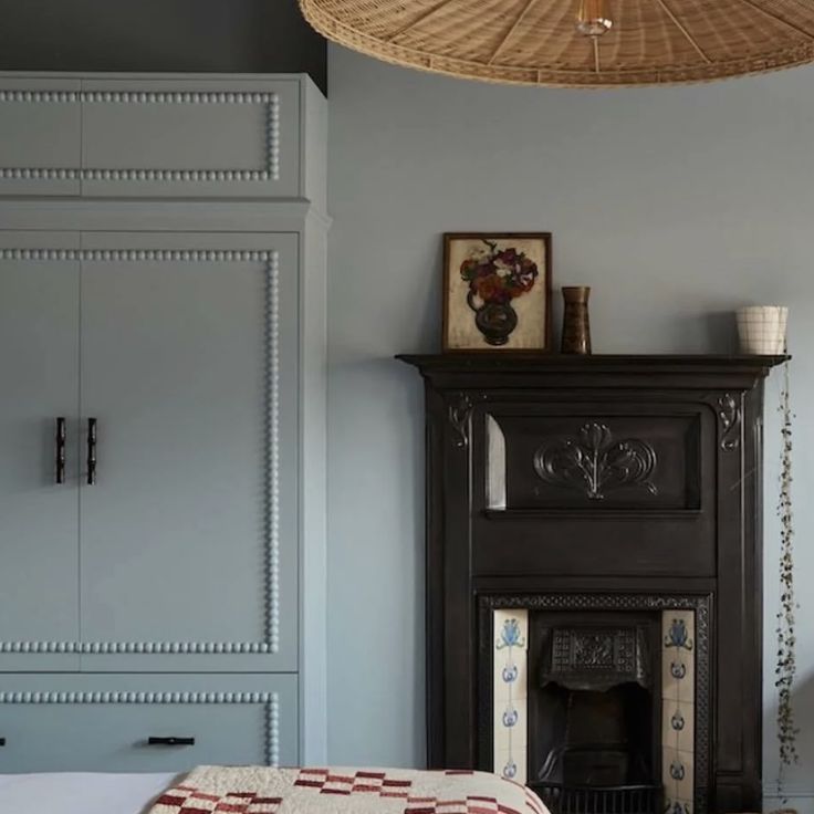 a bedroom with a bed, fireplace and wicker basket hanging from the ceiling above it