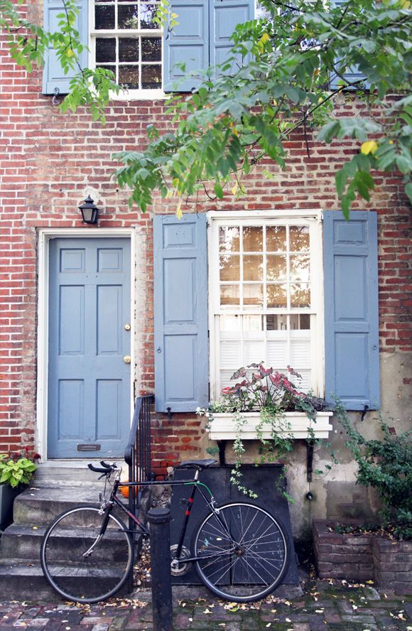 a bicycle parked in front of a brick building with blue shutters