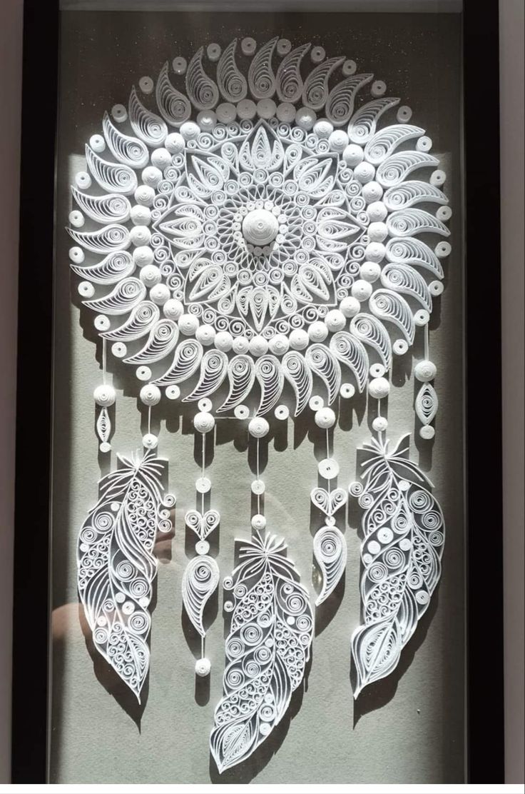 an intricately designed wall hanging made out of white paper with beads and pearls on it