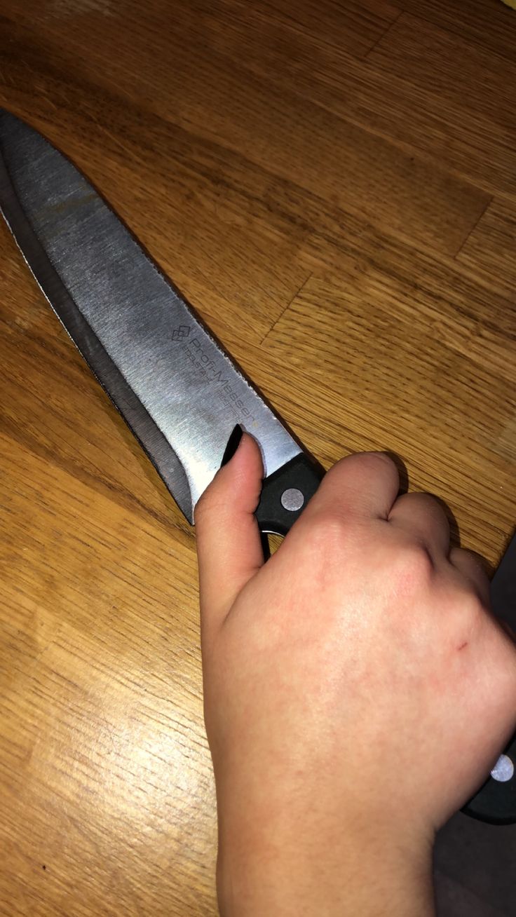 a person holding a knife on top of a wooden table