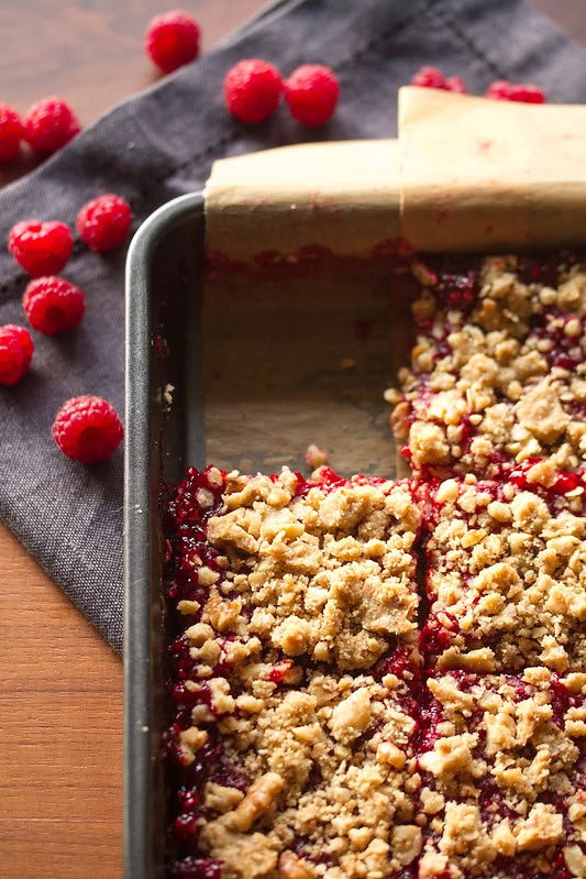 raspberry crumb bars in a pan with a wooden spatula on the side