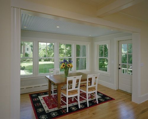 a table and chairs in a room with large windows on both sides of the room