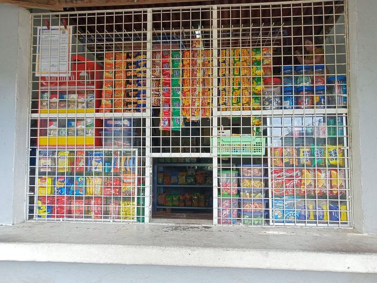 an open window with lots of food on display in it's front wall and behind the glass there is a carton of orange juice