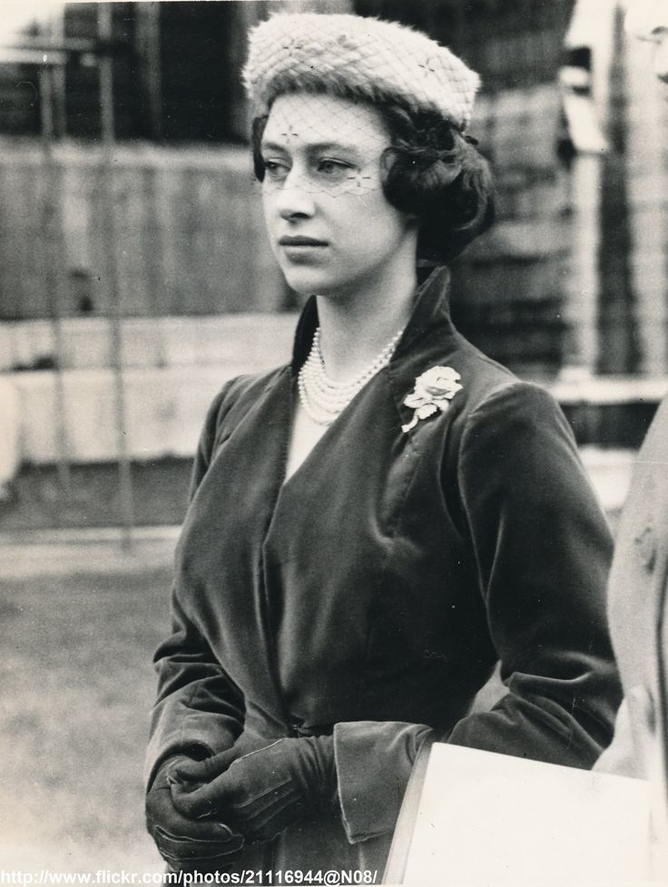 an old black and white photo of a woman wearing a hat with flowers on it